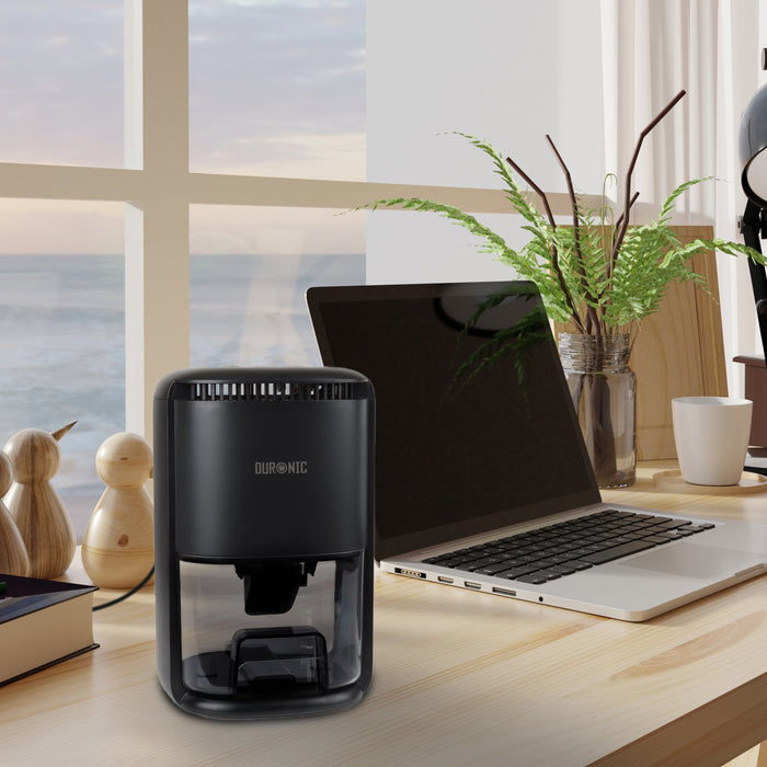 Duronic DH07 BK mini dehumidifier placed on desk alongside laptop