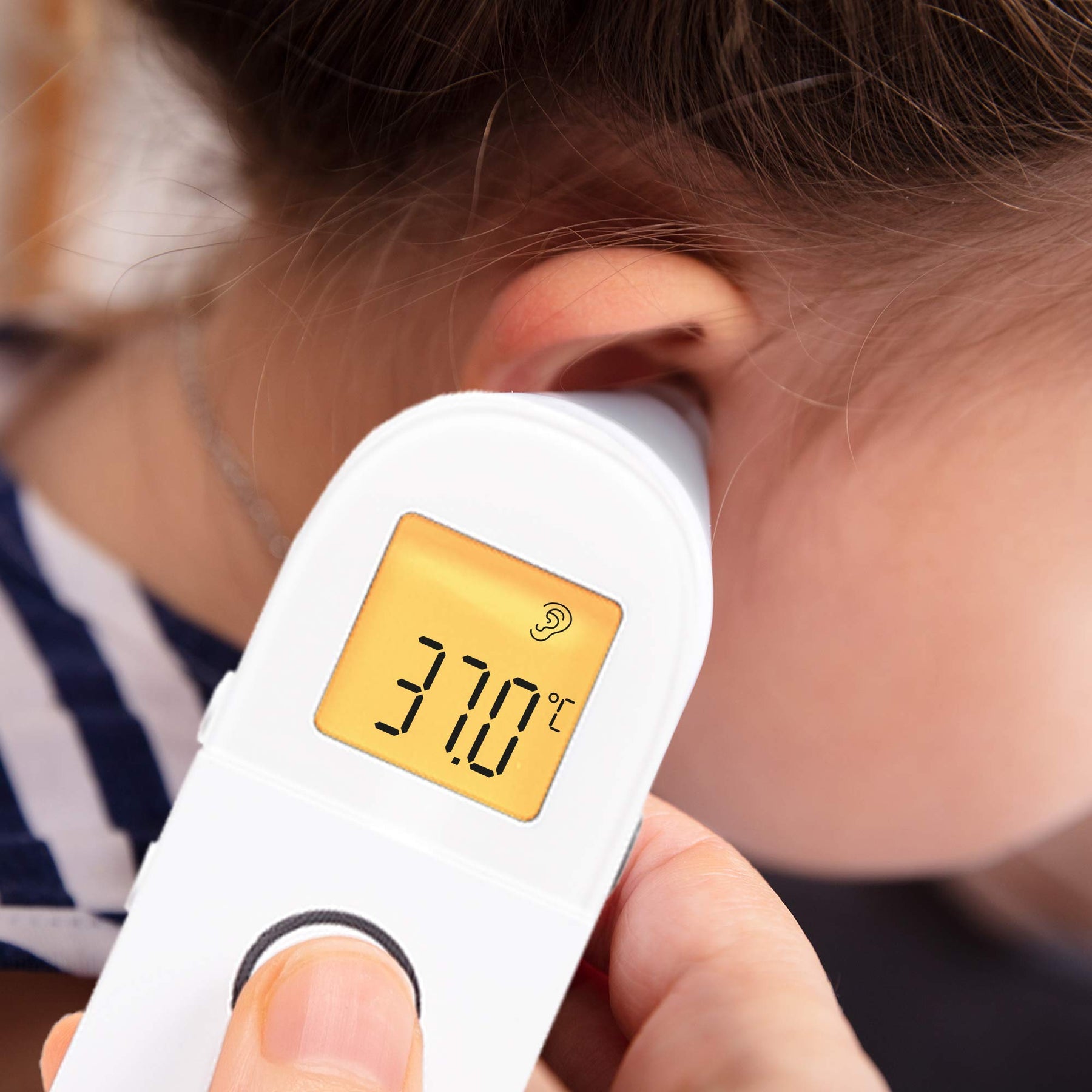 Digital ear thermometer measuring a child's temperature, displaying °C, for a family winter health and thermometer buying guide.