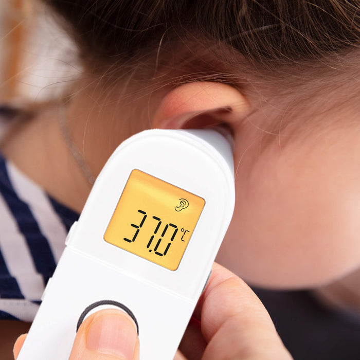 Digital ear thermometer measuring a child's temperature, displaying °C, for a family winter health and thermometer buying guide.