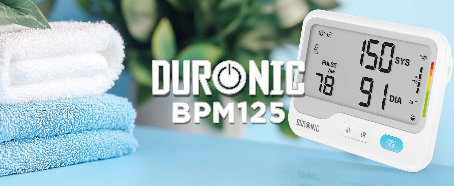 Duronic digital blood pressure monitor displaying blood pressure and pulse readings, pictured beside folded towels in a home setting.