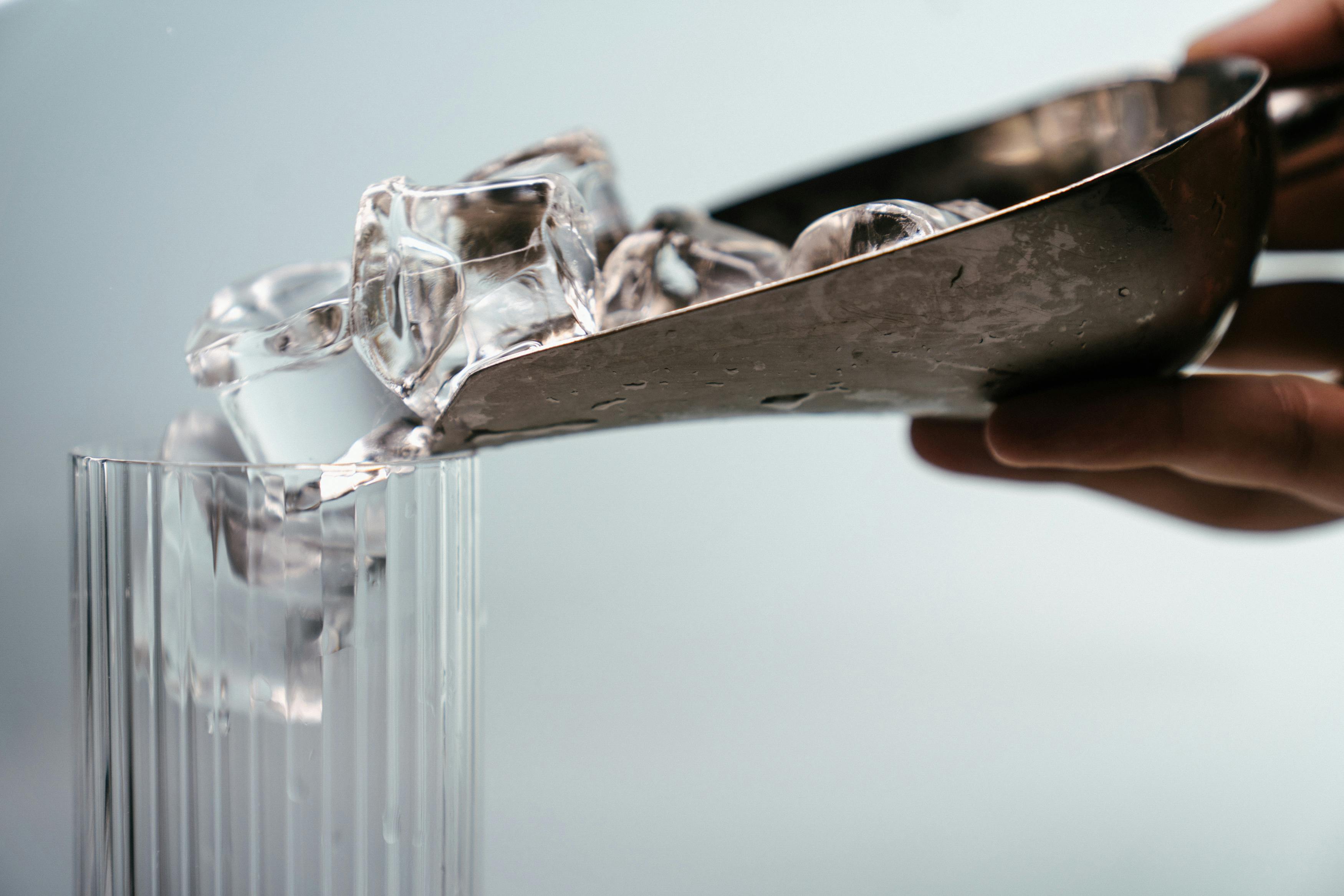 Ice being put into a glass using an ice scooper