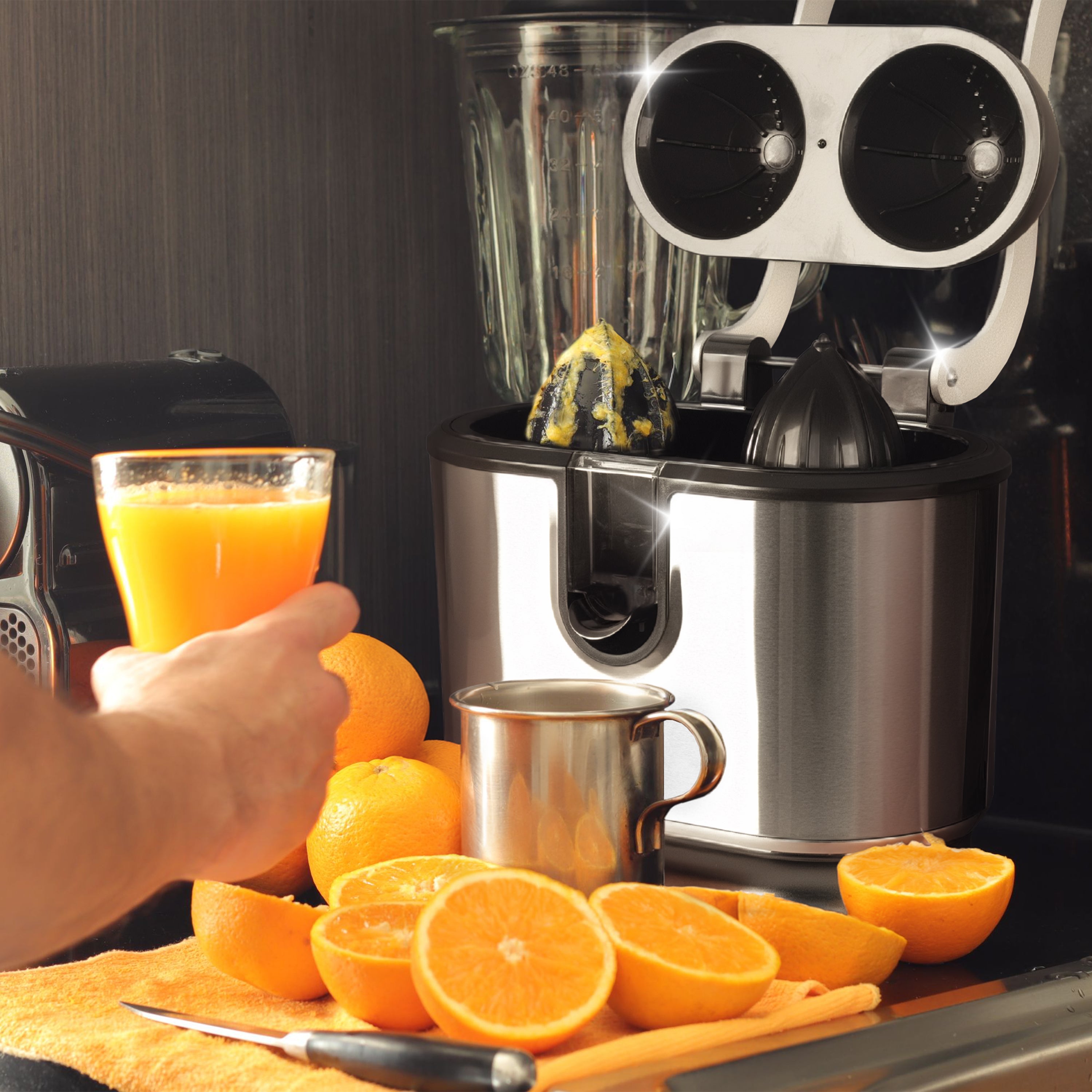 Duronic Electric Citrus Juicer with person holding a glass of fresh orange juice