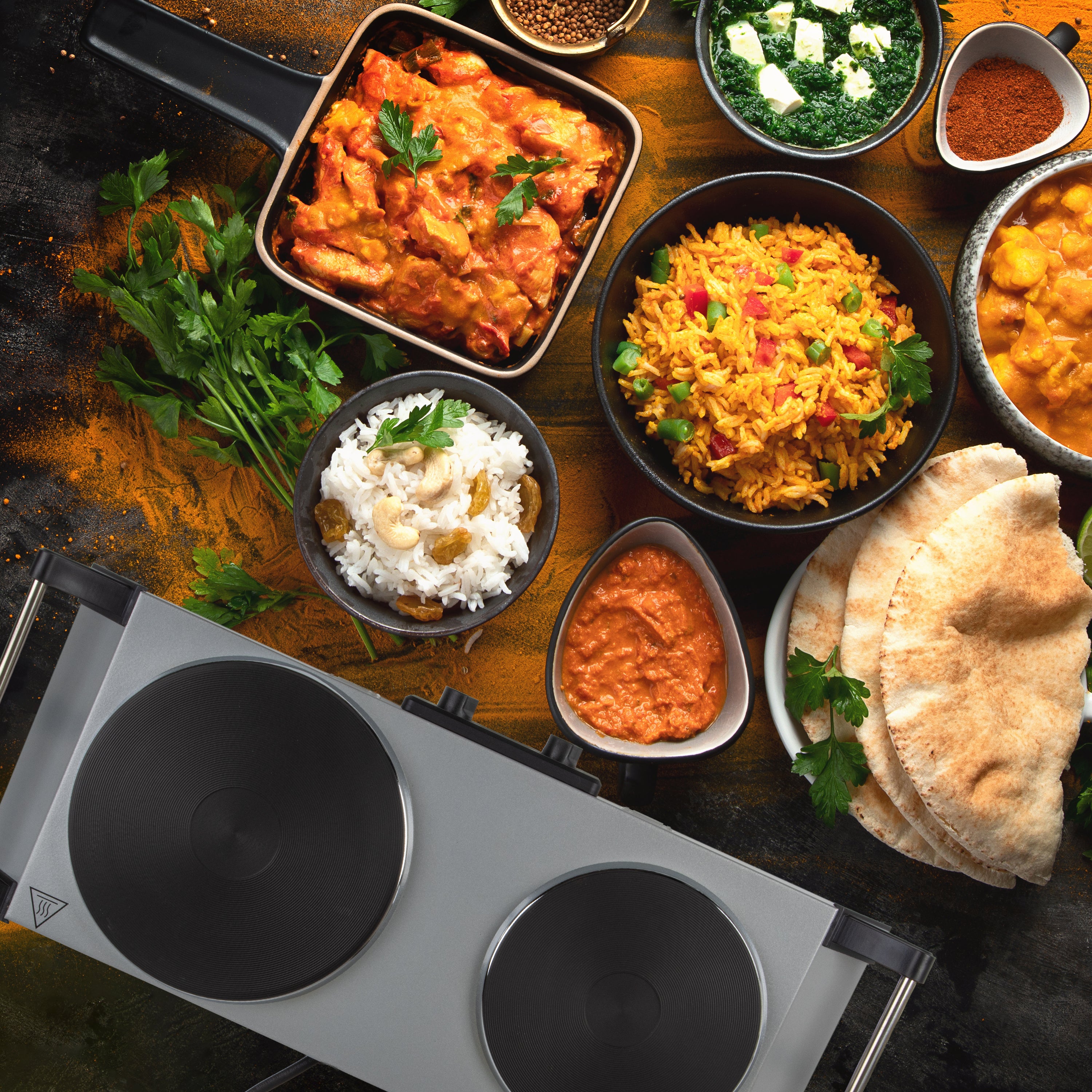 Duronic Electric Hot Plate shown displayed alongside Indian dishes like chicken curry, yellow rice, and naan.