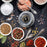 Duronic Electric Salt and Pepper Grinder with top view of colorful spices, gourmet salts, pepper grinder, and vintage spoons on dark slate.