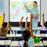 Duronic Tripod Projector Screen with a teacher points at a world map while students raise hands.