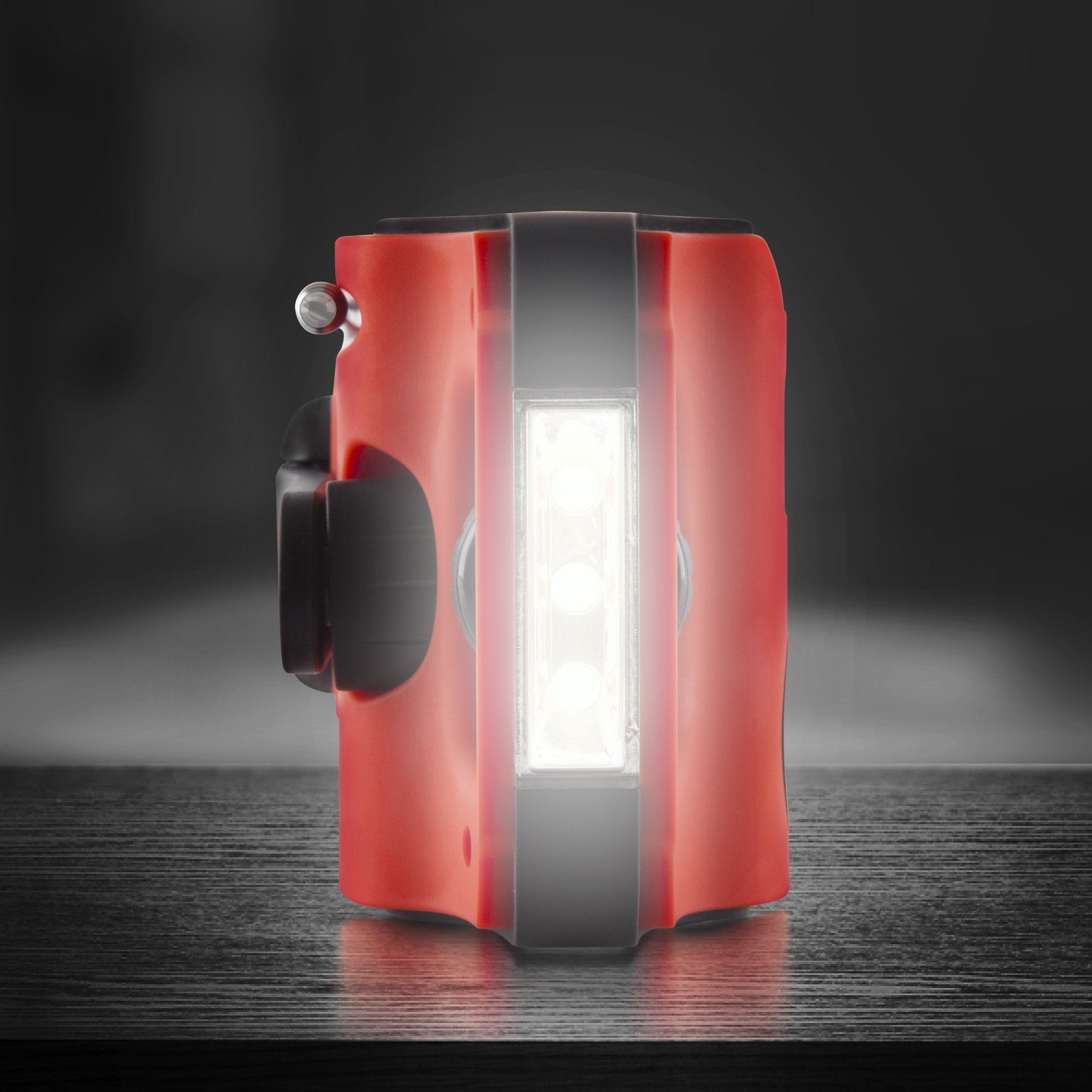 Duronic Wind Up Solar Powered Flashlight Radio Apex Compact red portable LED work light with three bright glowing bulbs resting on dark surface.
