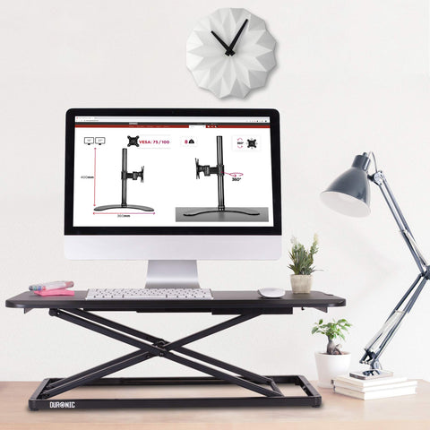 Duronic Sit-Stand Desk with a monitor, clock, and desk lamp.