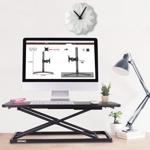 Duronic Sit-Stand Desk with a monitor, clock, and desk lamp.