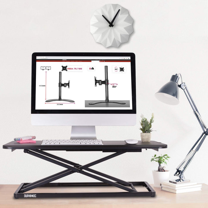 Duronic Sit-Stand Desk with a monitor, clock, and desk lamp.