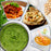A collage of various blended foods including a large bowl of fresh green pesto, spaghetti bolognese, creamy hummus with pita, and smooth orange baby puree.