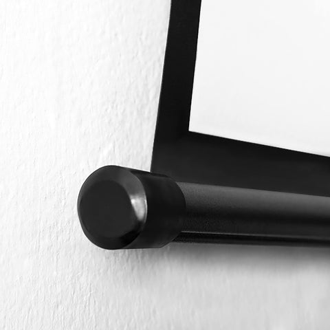 Close up view of a black metal scroll frame end cap on a white wall