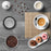 Duronic Electric Coffee Grinder with a cup, three donuts, loose coffee beans, and cream.