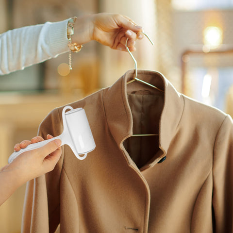 Duronic Lint Roller cleaning a tan wool coat hanging on a gold hanger.