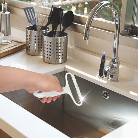 Duronic Lint Shaver being held over a modern stainless steel sink.