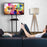 Duronic Mobile TV Stand on Wheels with a man on a sofa holding a remote control, watching a Duronic television on a rolling stand.