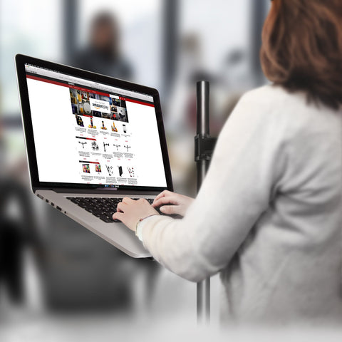 Duronic Monitor and Laptop Stand with a person using a laptop mounted on a pole stand while browsing an e-commerce website.