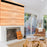 Duronic Projector Screen mounted above a wood paneled wall and fireplace in a living room.