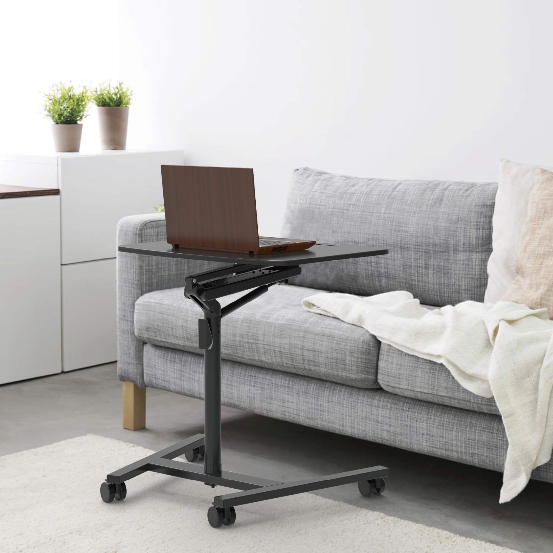 Duronic Projector Stand with a laptop on top, positioned next to a gray sofa.
