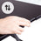 Duronic Sit-Stand Desk with hand squeezing a lever on a black standing desk converter to adjust its height.
