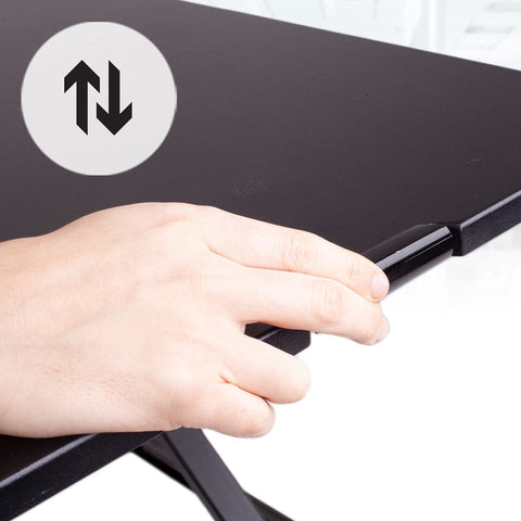 Duronic Sit-Stand Desk with hand squeezing a lever on a black standing desk converter to adjust its height.