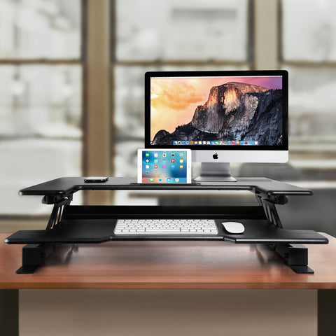 Duronic Sit-Stand Desk with iMac, iPad, keyboard, and mouse on wooden desk.
