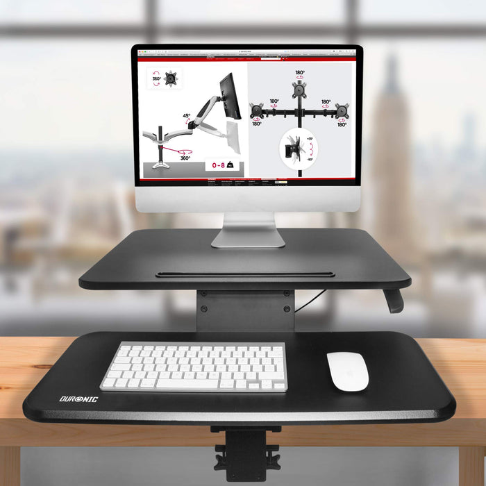 Duronic Sit-Stand Desk with keyboard tray clamped to wooden table holding a computer.