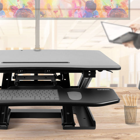 Duronic Sit-Stand Desk with keyboard tray, supporting dual monitors on a wooden office desk.