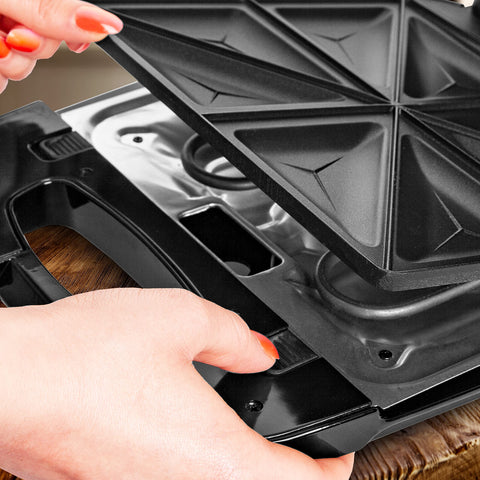 Duronic Spare Plates removing a non-stick triangular sandwich plate from a black electric panini press.