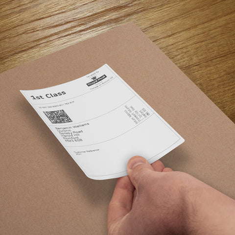 Duronic Thermal Labels with hand peeling a Royal Mail 1st Class shipping label onto a brown cardboard package.